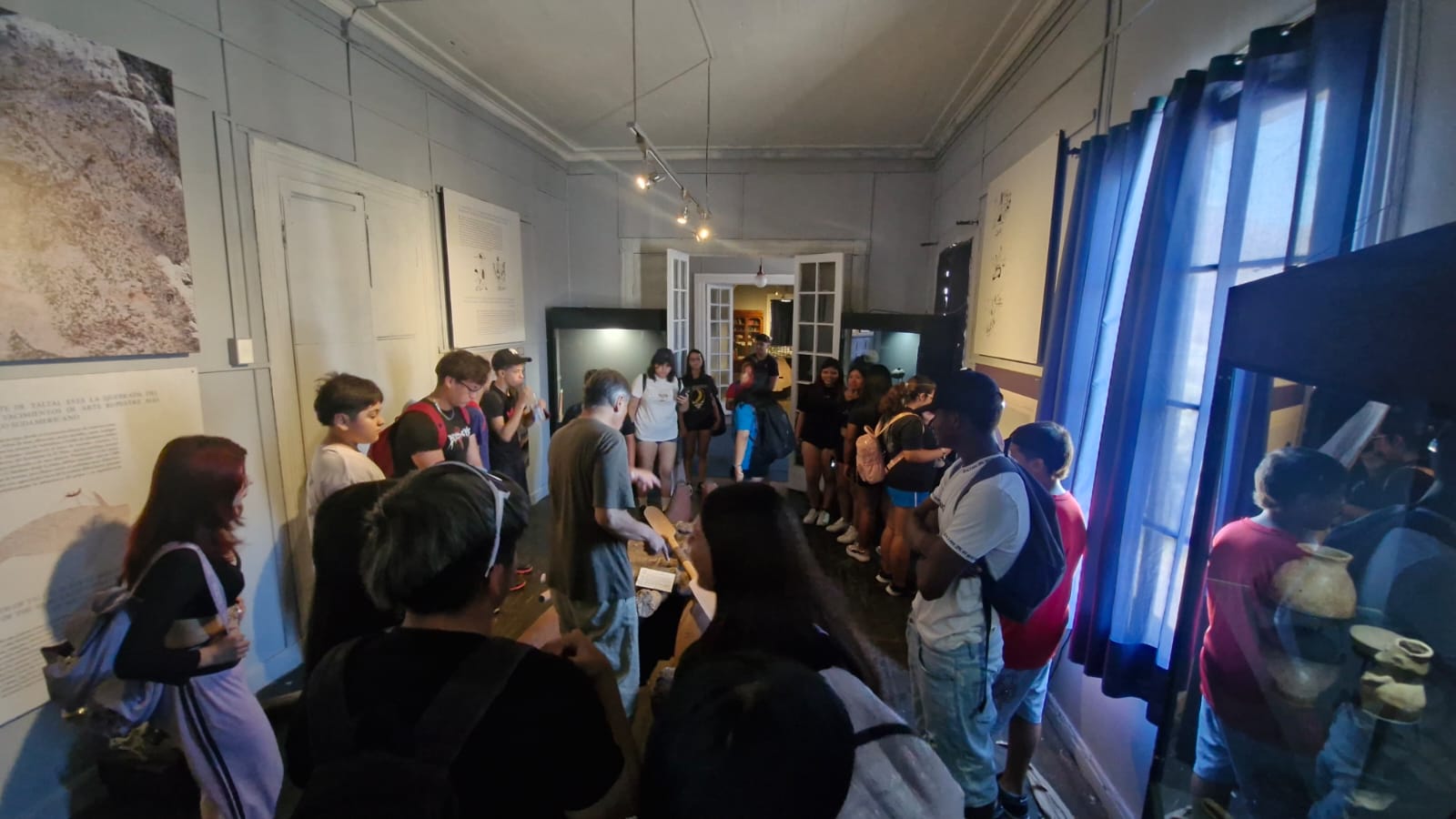 Guía explicando detalles de una exhibición arqueológica a jóvenes en el museo.