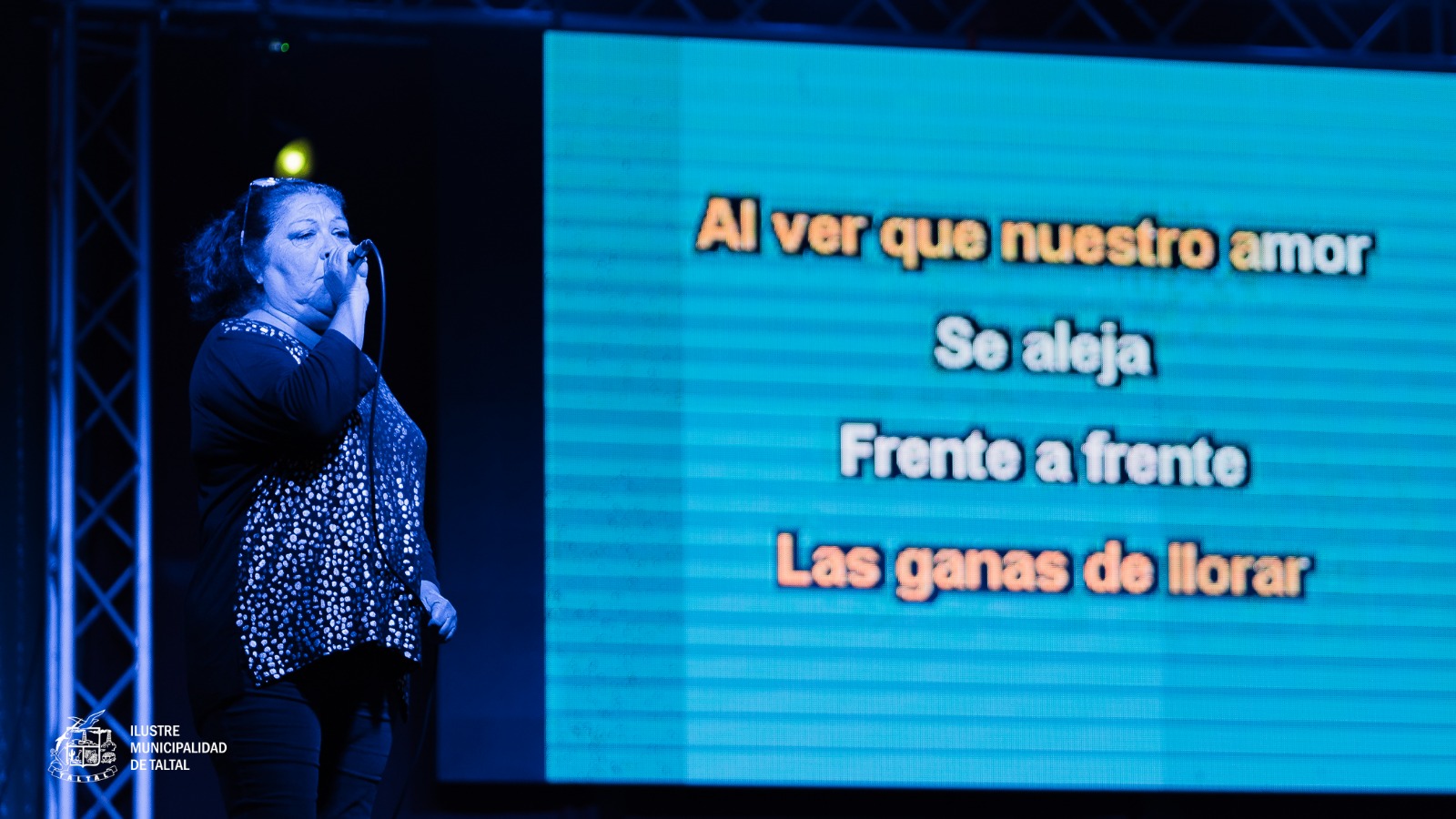 Vecina de Taltal interpretando una canción en la pantalla gigante durante la Noche de Karaoke.