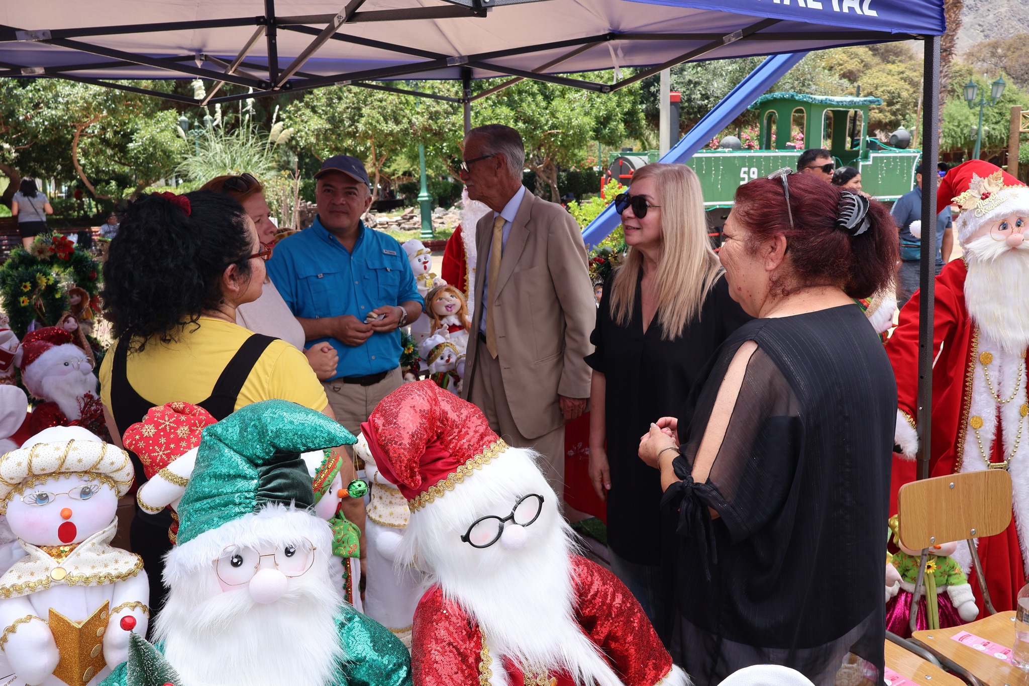 Vecinos y autoridades dialogan en un stand de manualidades y decoración navideña en el Día INTEGRAR en Taltal.
