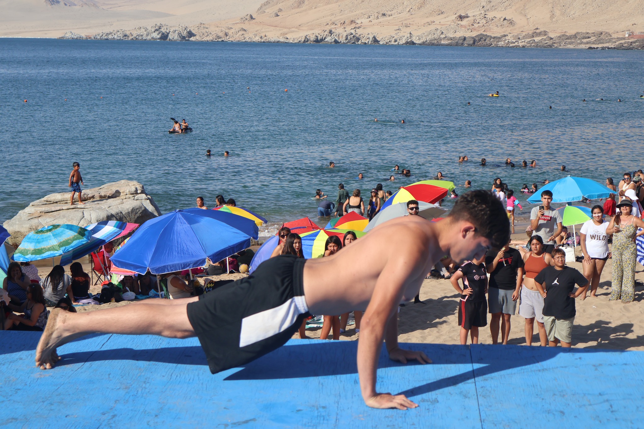 Joven participando en concurso de flexiones sobre el escenario en la playa Cifuncho.
