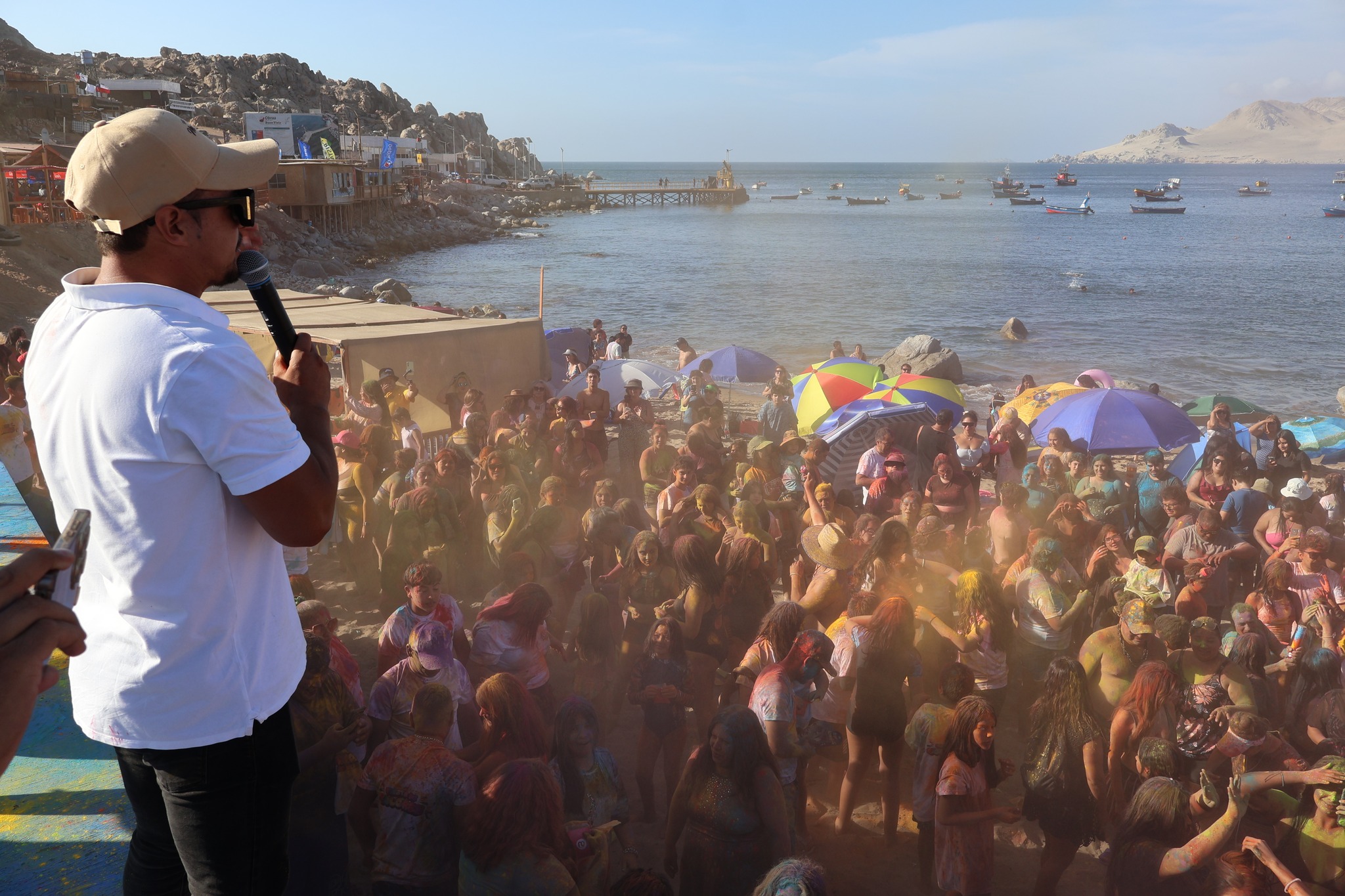Vista desde el escenario del DJ hacia la multitud durante el sunset musical frente al mar.
