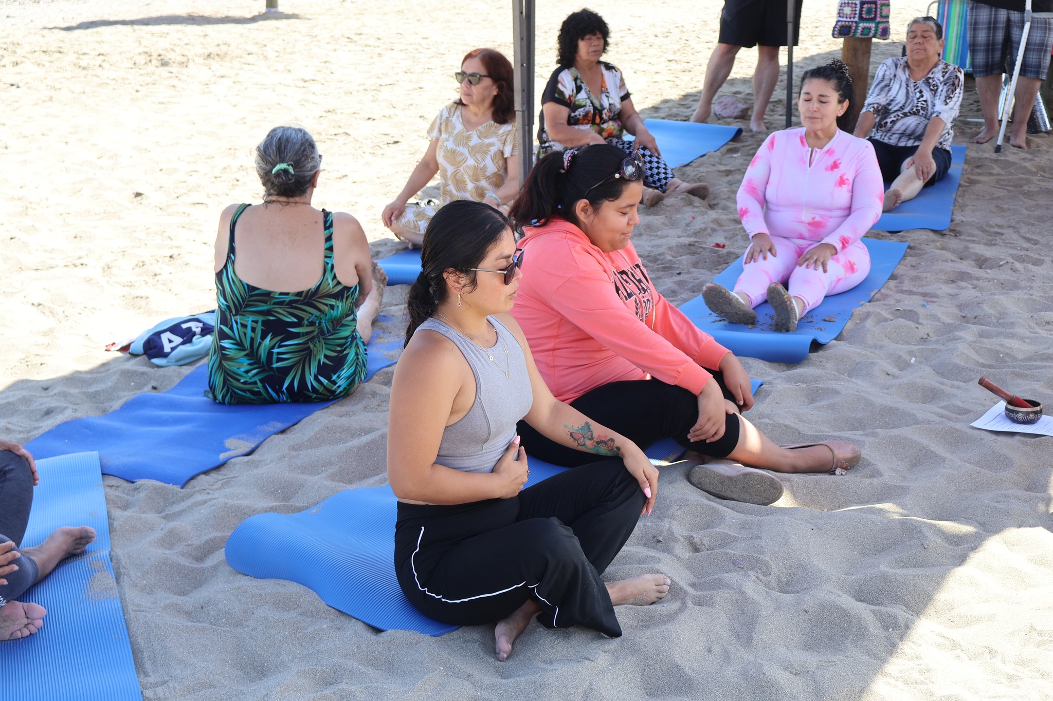 Mujeres participando en ejercicios de meditación y respiración a orillas del mar.