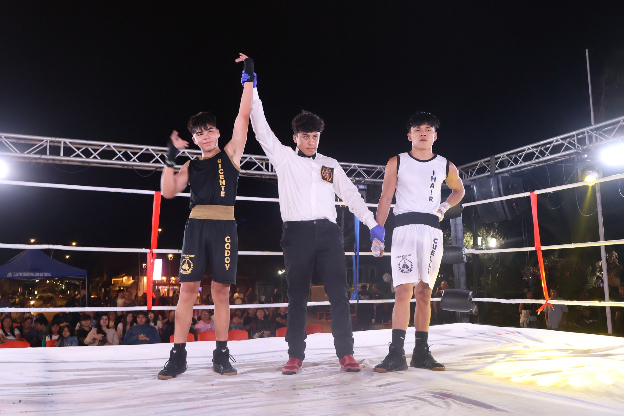 Árbitro levantando la mano del vencedor en señal de triunfo tras un arduo combate en la velada deportiva.