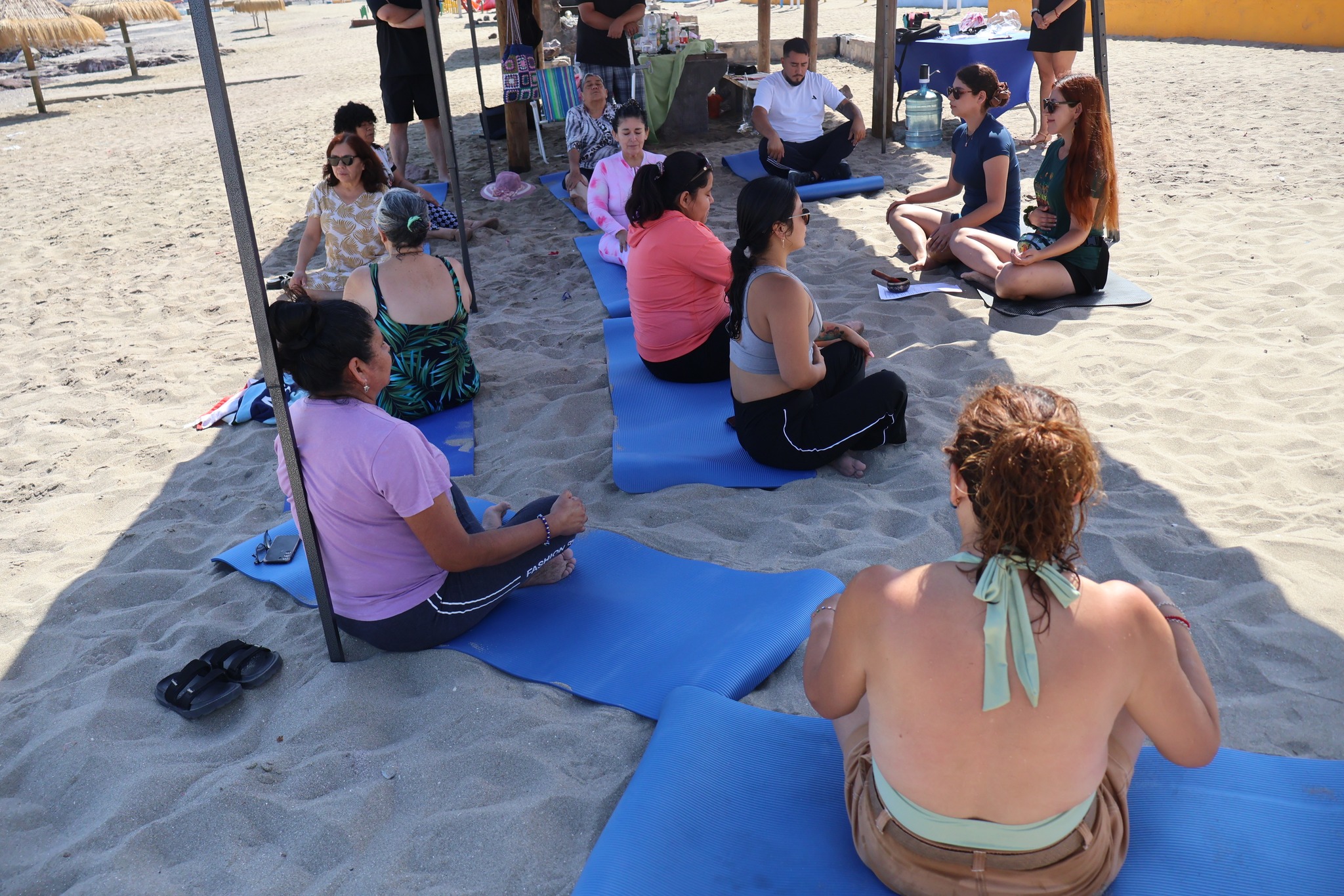 Personas en postura de relajación durante una sesión de sonoterapia en la arena.