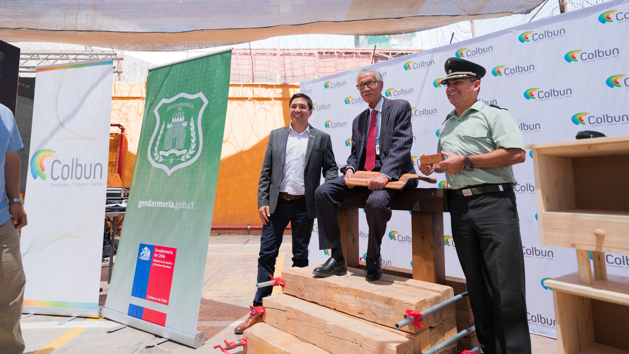 Representantes de Colbún y Gendarmería posan con piezas de madera elaboradas en el marco del Taller de Carpintería del CET de Taltal.