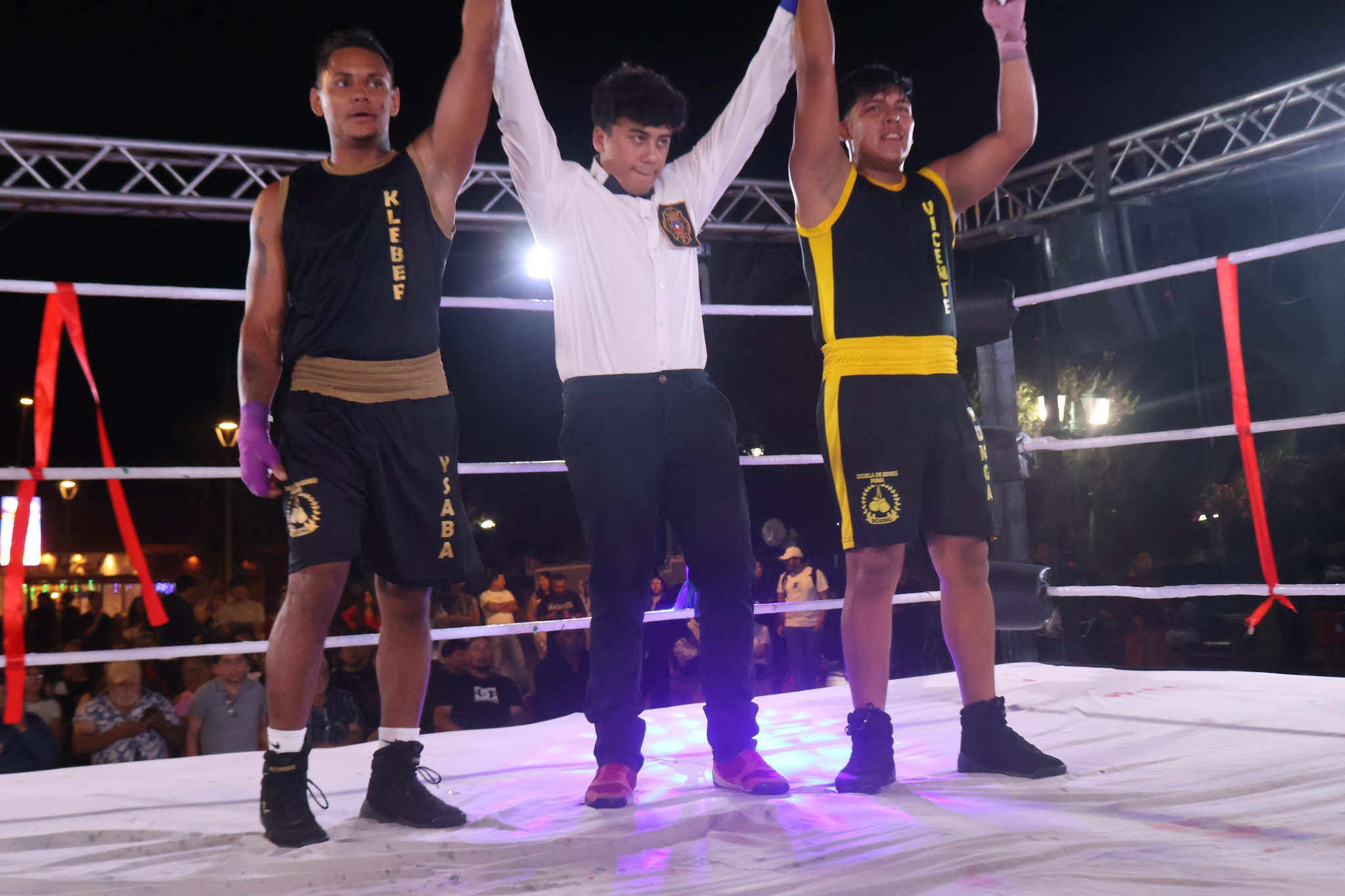 El árbitro central levantando los brazos de los púgiles locales tras finalizar un arduo combate en la velada deportiva de Taltal.