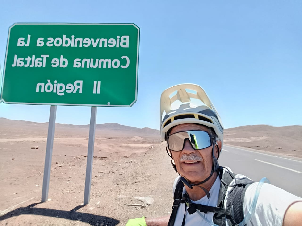 Pedro Lemus se fotografía en ruta junto a un cartel de “Bienvenidos a la Comuna de Taltal”, durante su viaje en bicicleta.