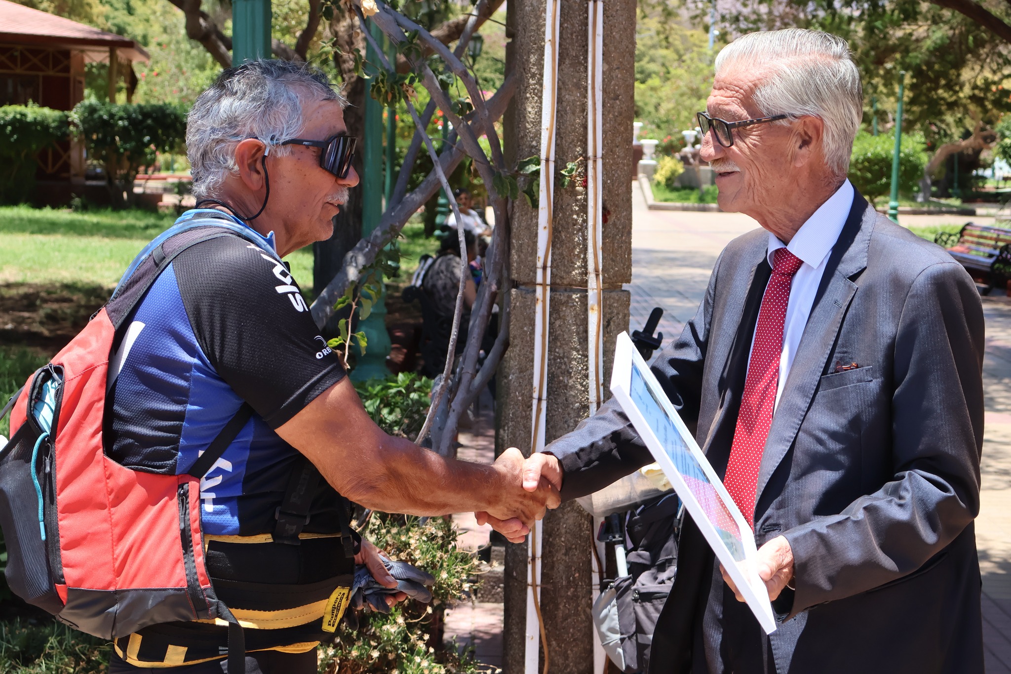 Pedro Lemus estrecha la mano de una autoridad local durante la entrega de reconocimiento tras su histórica travesía en bicicleta.