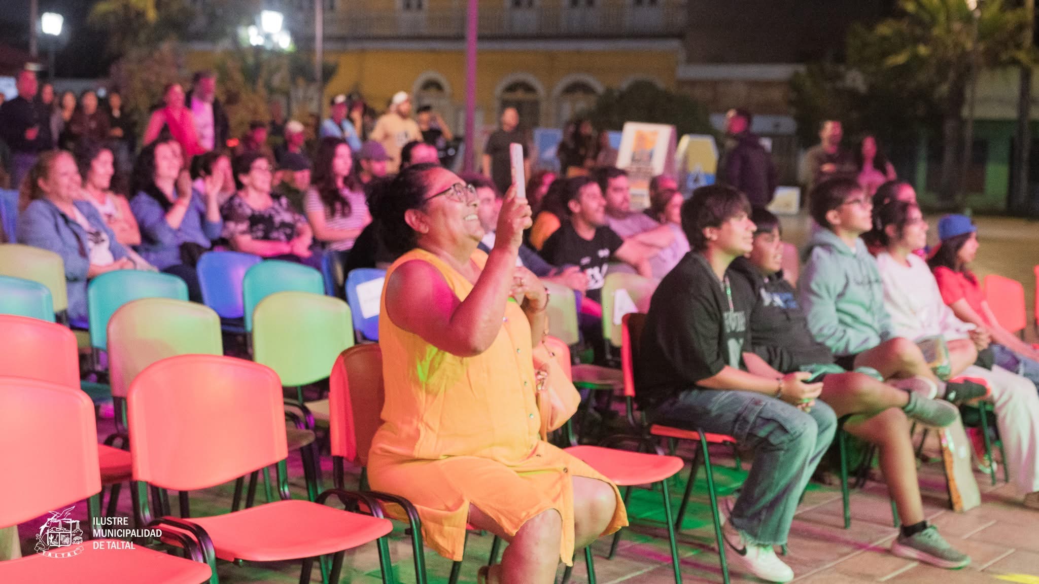 Cientos de personas disfrutan sentadas de la actividad recreativa y cultural al aire libre.