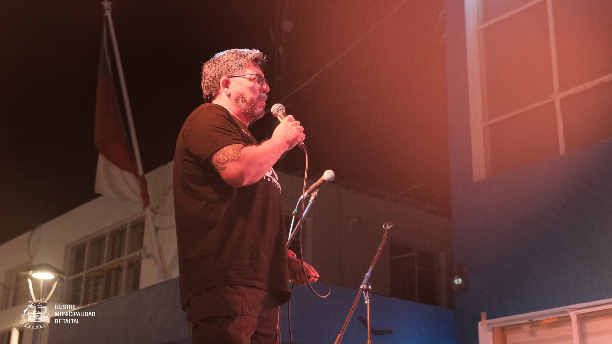 Vecino de la comuna demostrando su talento vocal en el escenario iluminado de la plaza.