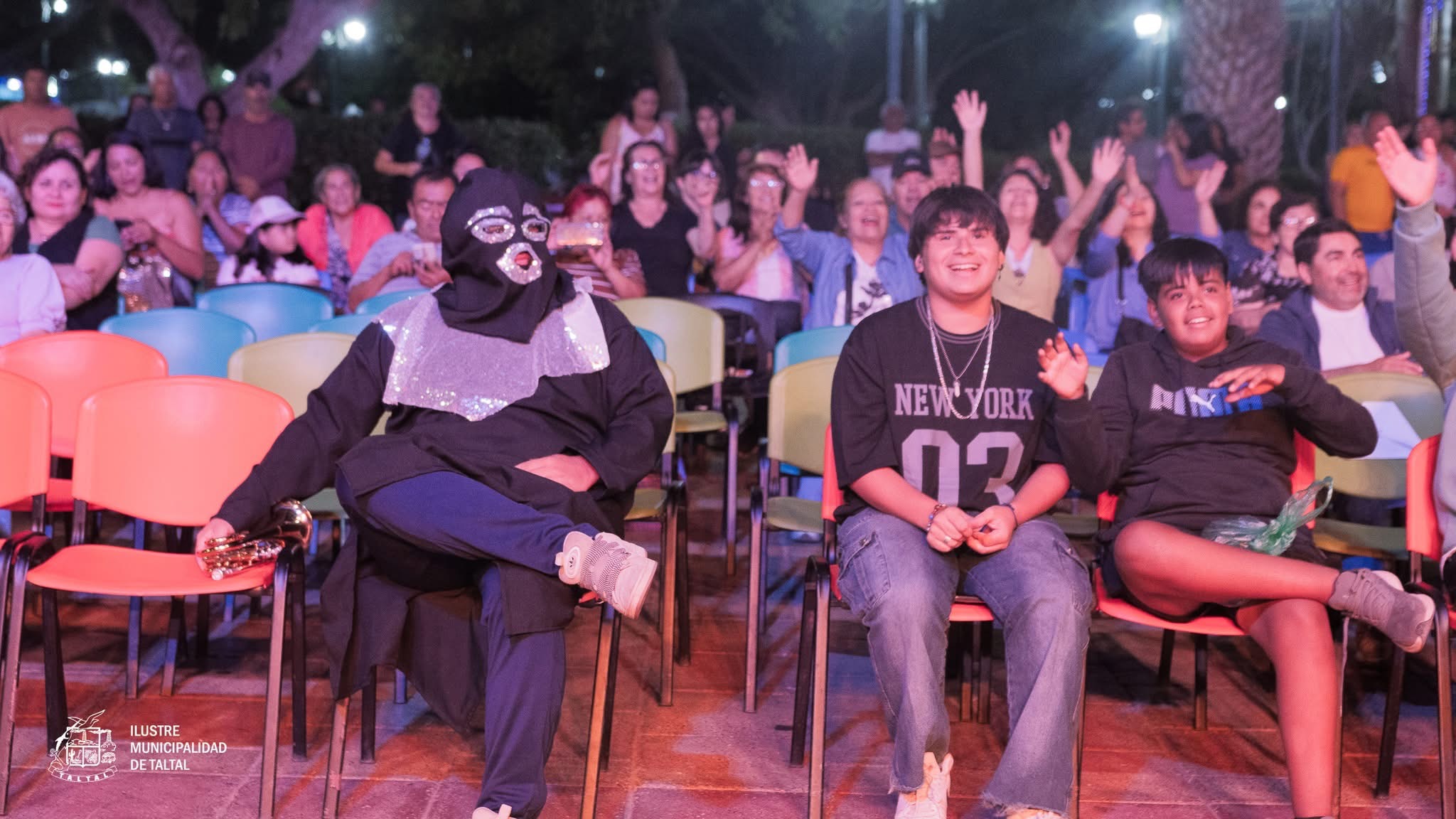 Asistentes sentados y disfrutando del show de karaoke en un ambiente familiar nocturno.