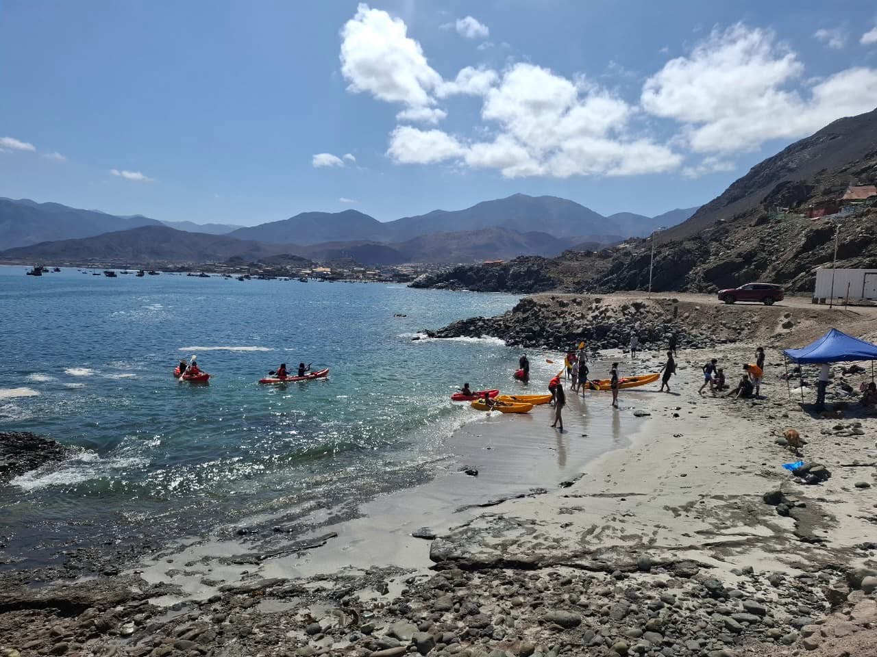 Vista panorámica de la bahía con niños practicando kayak cerca de la orilla.
