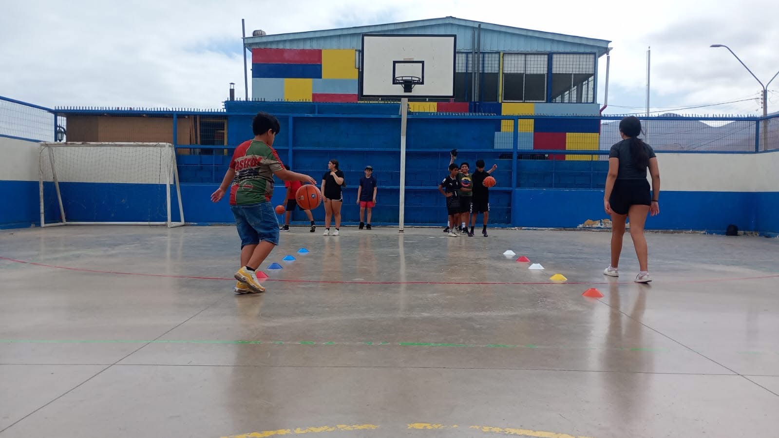Alumno de espalda avanzando hacia el aro en entrenamiento de básquetbol.