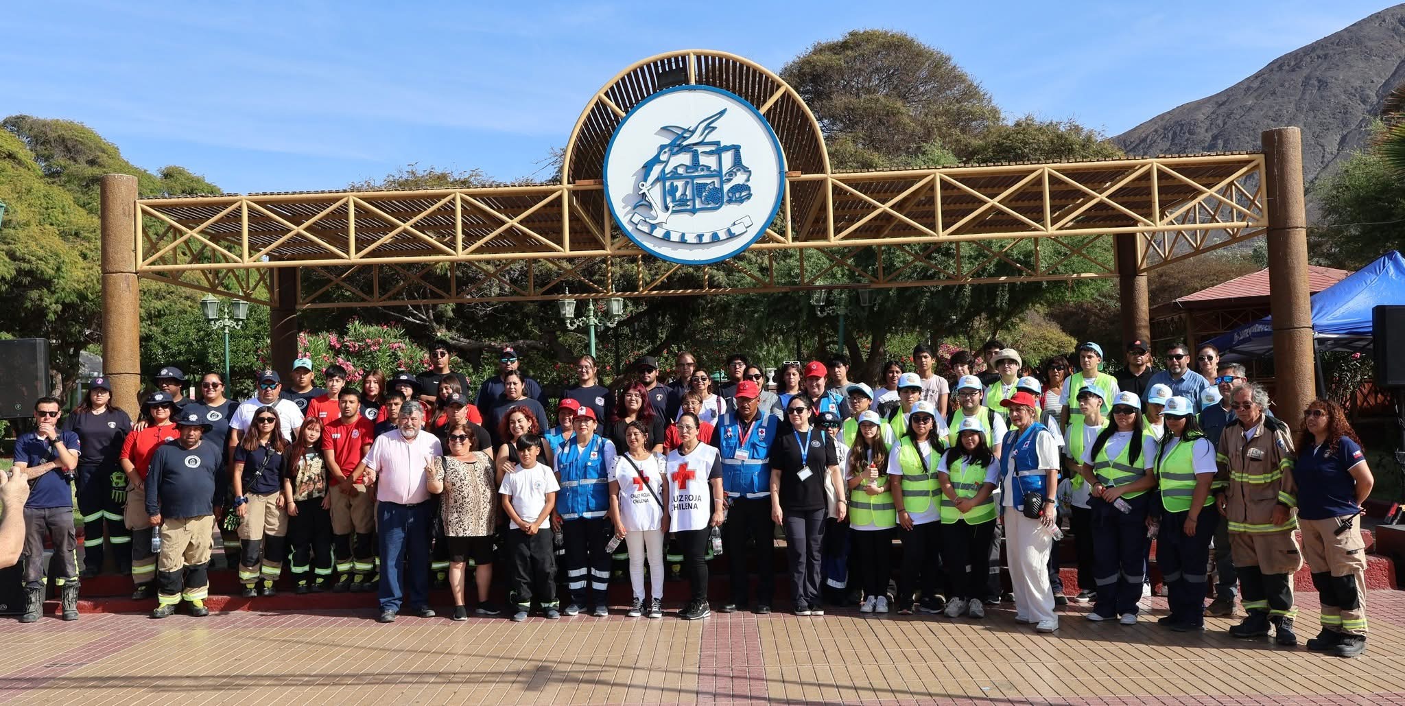 Voluntarios de Cruz Roja, Bomberos y Team de Verano posan frente al hito de Taltal por campaña solidaria.