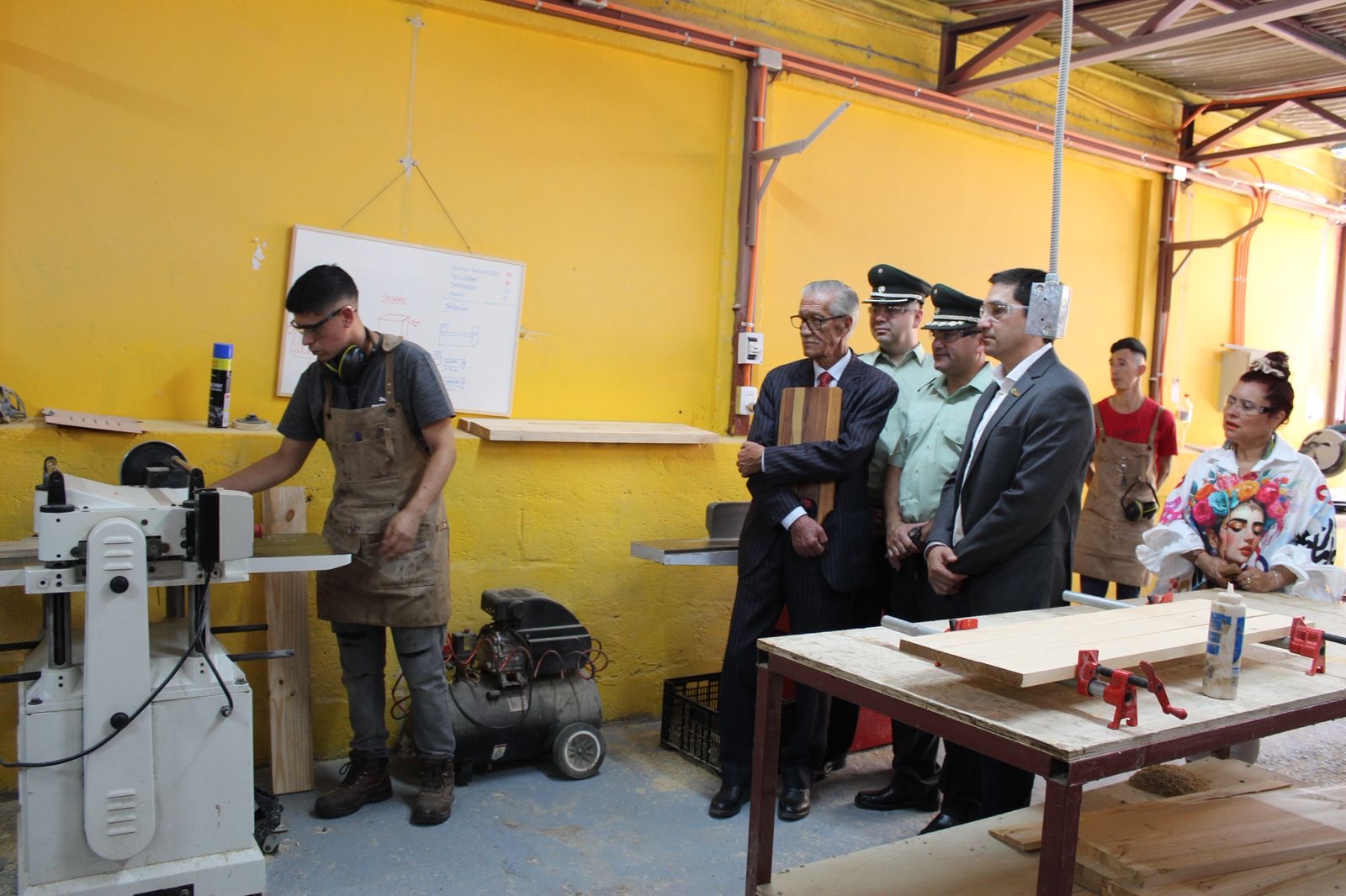Participante del CET de Taltal opera maquinaria en el nuevo taller de carpintería mientras autoridades observan la demostración.
