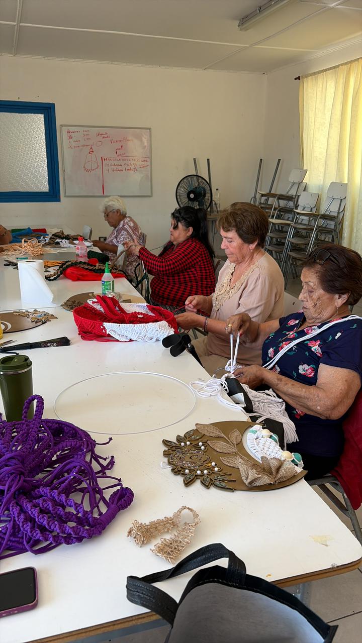 Grupo de 17 vecinas trabajando intensamente en sus tejidos de macramé durante el taller financiado por Colbún.