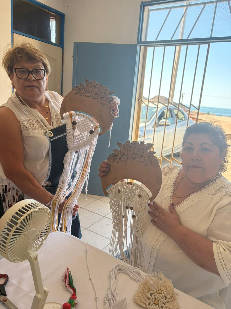 Dos alumnas del taller exhibiendo sus mandalas terminados, reflejando el compañerismo y éxito del curso.