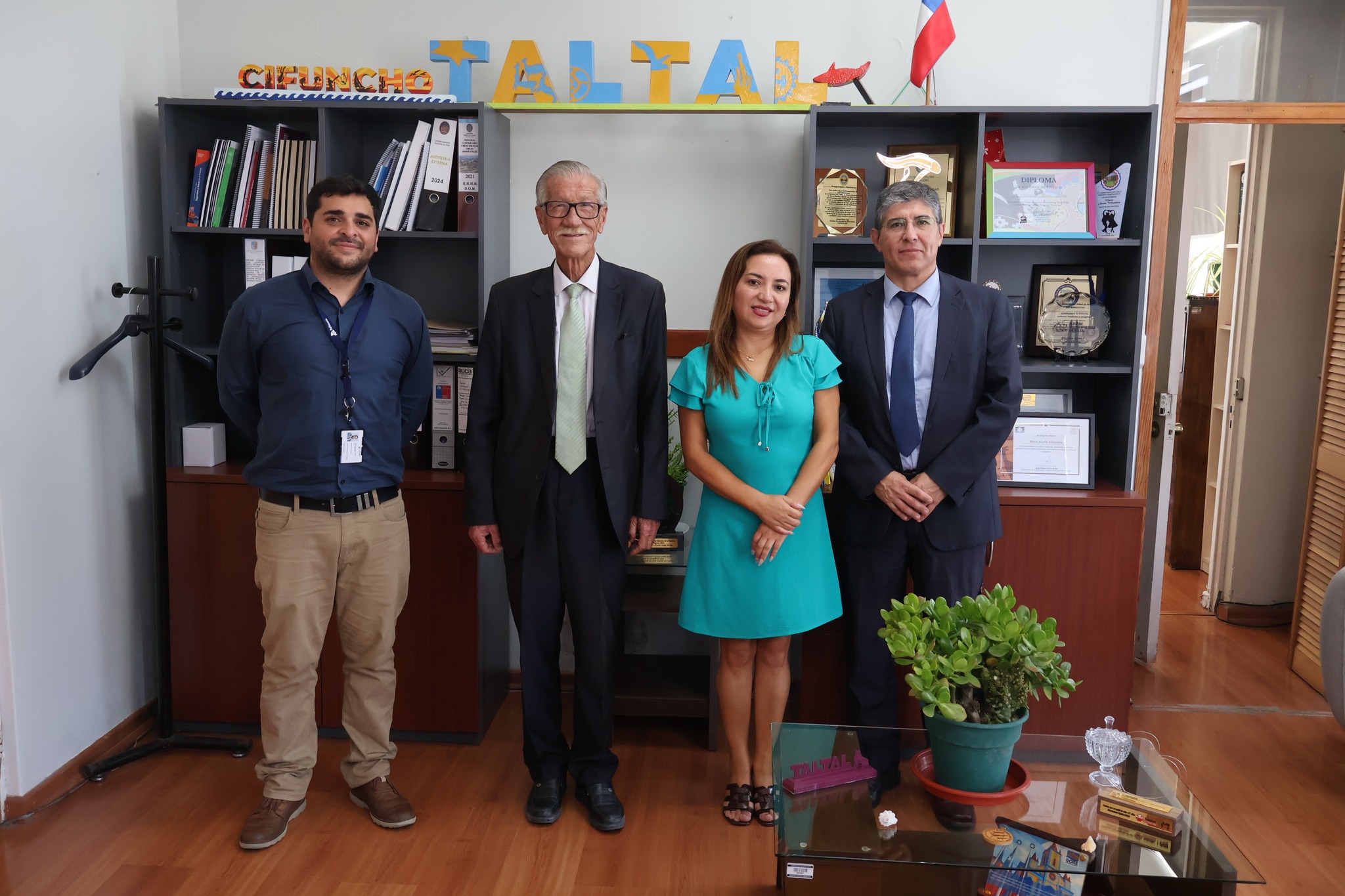 Alcalde Mario Acuña Villalobos junto a la Defensora Regional Karina Reyes Gálvez, Stephen Kendall Craig y Fabián Espejo Carvajal en reunión de coordinación institucional para fortalecer acceso a la justicia en Taltal, enero 2026. Fondo con estantería "CIFUNCHO TALTAL" y reconocimientos.