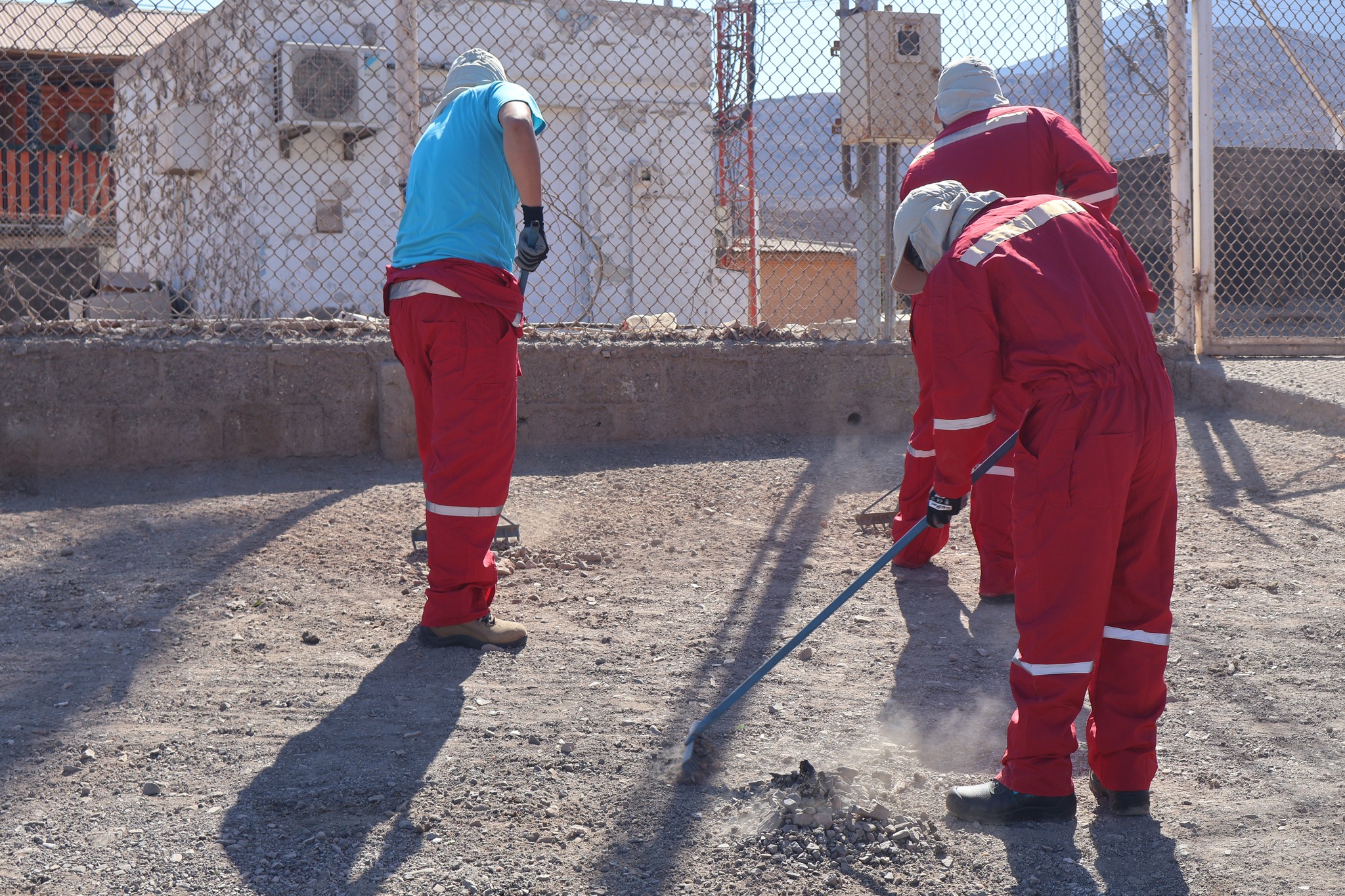Tres integrantes del Team Verano 2026 trabajando con rastrillos y palas en la limpieza y nivelación de Pasaje Entel, comuna de Taltal, durante jornada municipal de recuperación de espacios públicos, enero 2026.