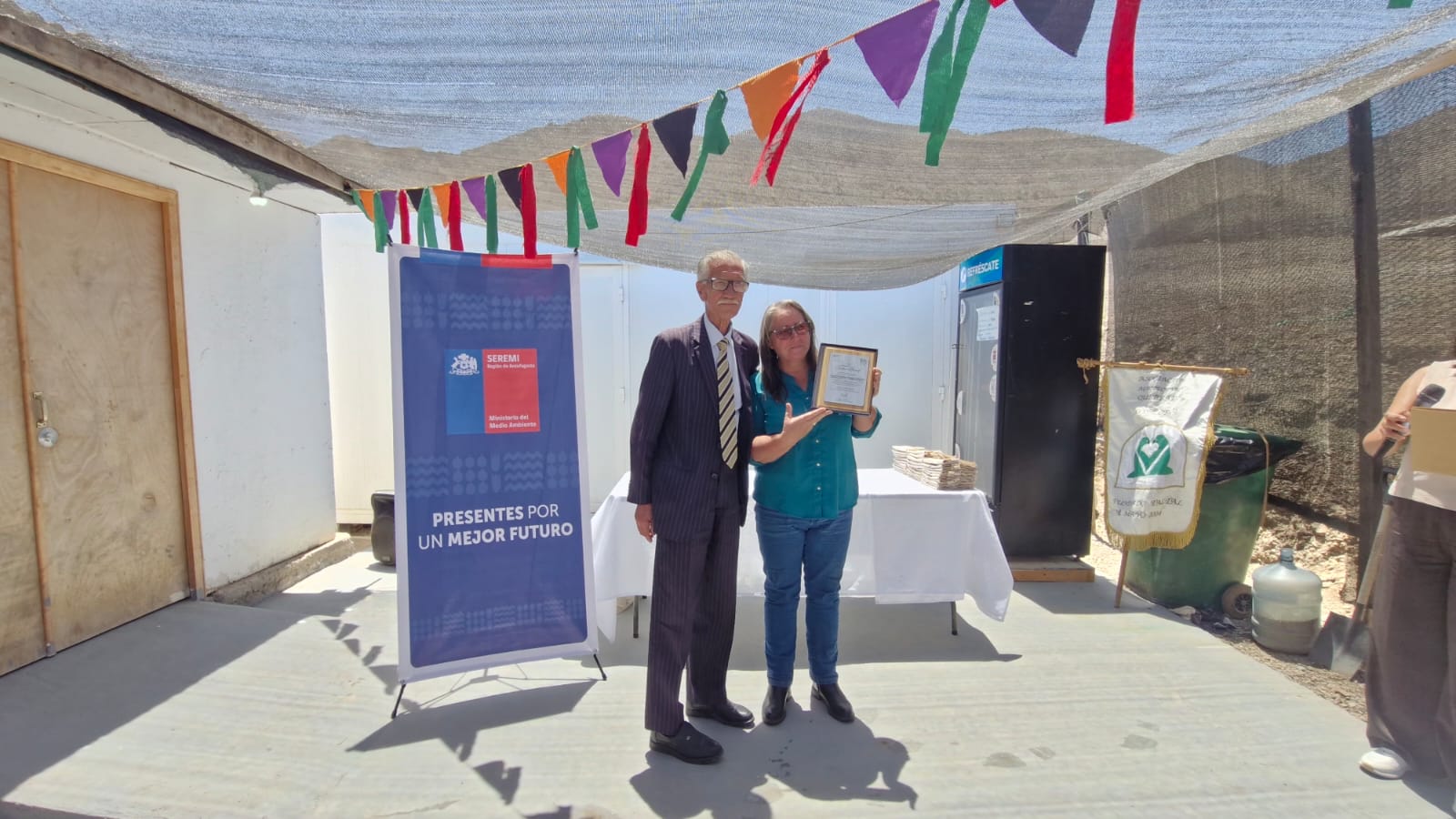Momento de premiación con galardón y pendón institucional durante ceremonia en Taltal.