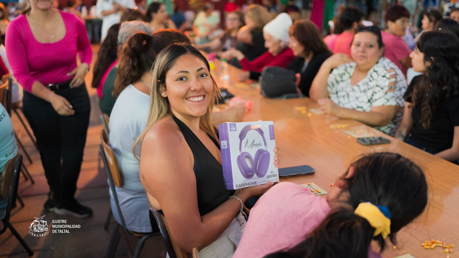 Vecina sonríe con su premio de audífonos durante la jornada del Gran Bingo Veraniego en Plaza Prat, Taltal, Verano 2026. Alta participación familiar en el programa Taltal en Movimiento.
