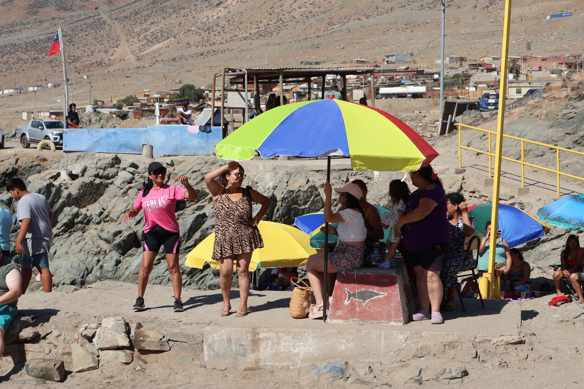 Familias se resguardan del sol y disfrutan del espectáculo en la Fiesta de Colores Paposo, parte de las actividades de verano de Taltal.