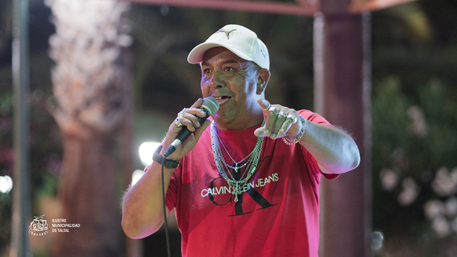Participante con polera “Gangster” y gorra dando thumbs up durante el Karaoke de Cumbias en Plaza de Armas de Taltal, febrero 2026.