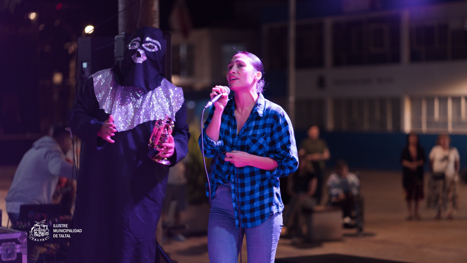 Participante cantando junto al Chacal de la Trompeta durante el Karaoke de Cumbias en Plaza de Armas de Taltal, verano 2026.