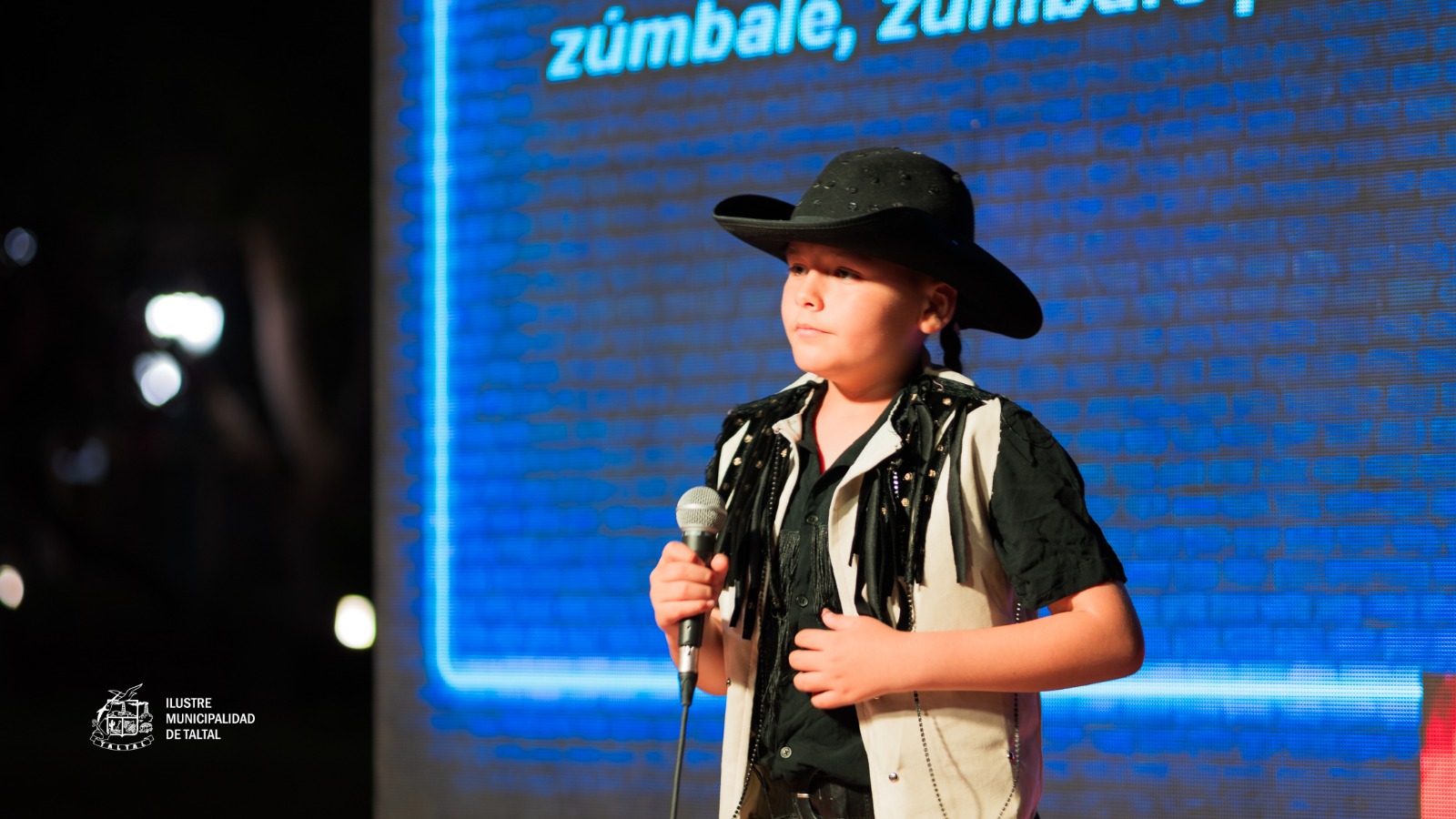Joven participante cantando con pasión en el Karaoke de Cumbias en la Plaza de Armas de Taltal, parte de la programación de verano 2026.