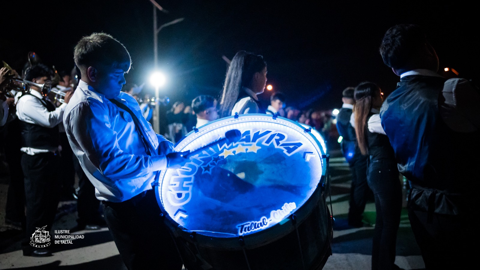 Joven percusionista con bombo Chunyi Wayra iluminado en procesión nocturna Virgen de Lourdes La Puntilla Taltal 2026