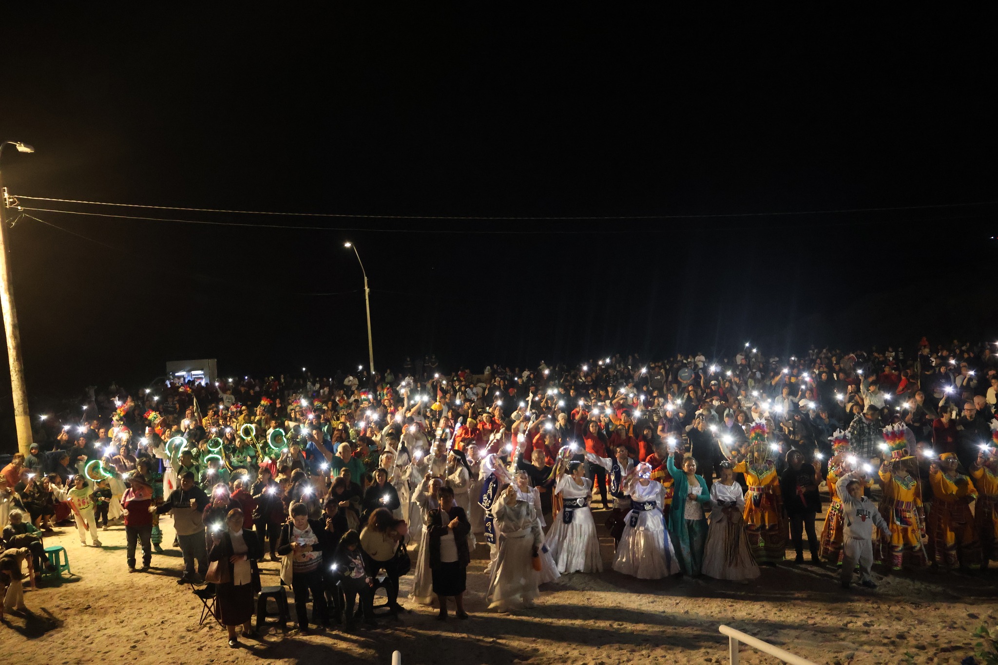 Vista aérea de miles de fieles y bailes religiosos en gruta durante descenso Virgen de Lourdes La Puntilla Taltal febrero 2026