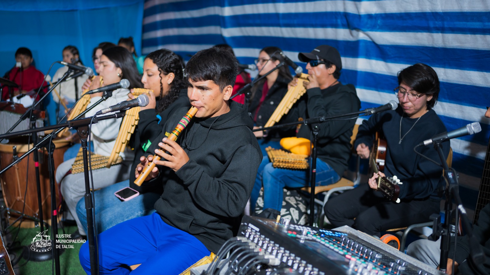 Jóvenes músicos tocando quenas y zampoñas en orquesta folclórica durante Fiesta Virgen de Lourdes sector La Puntilla Taltal febrero 2026