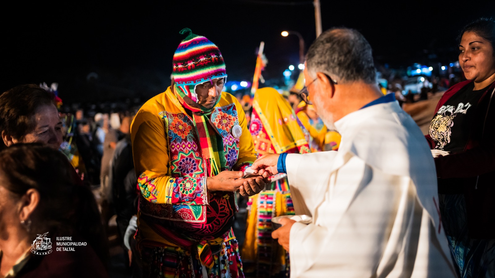 Bailarín religioso indígena recibe la comunión durante procesión nocturna Fiesta Virgen de Lourdes sector La Puntilla Taltal febrero 2026