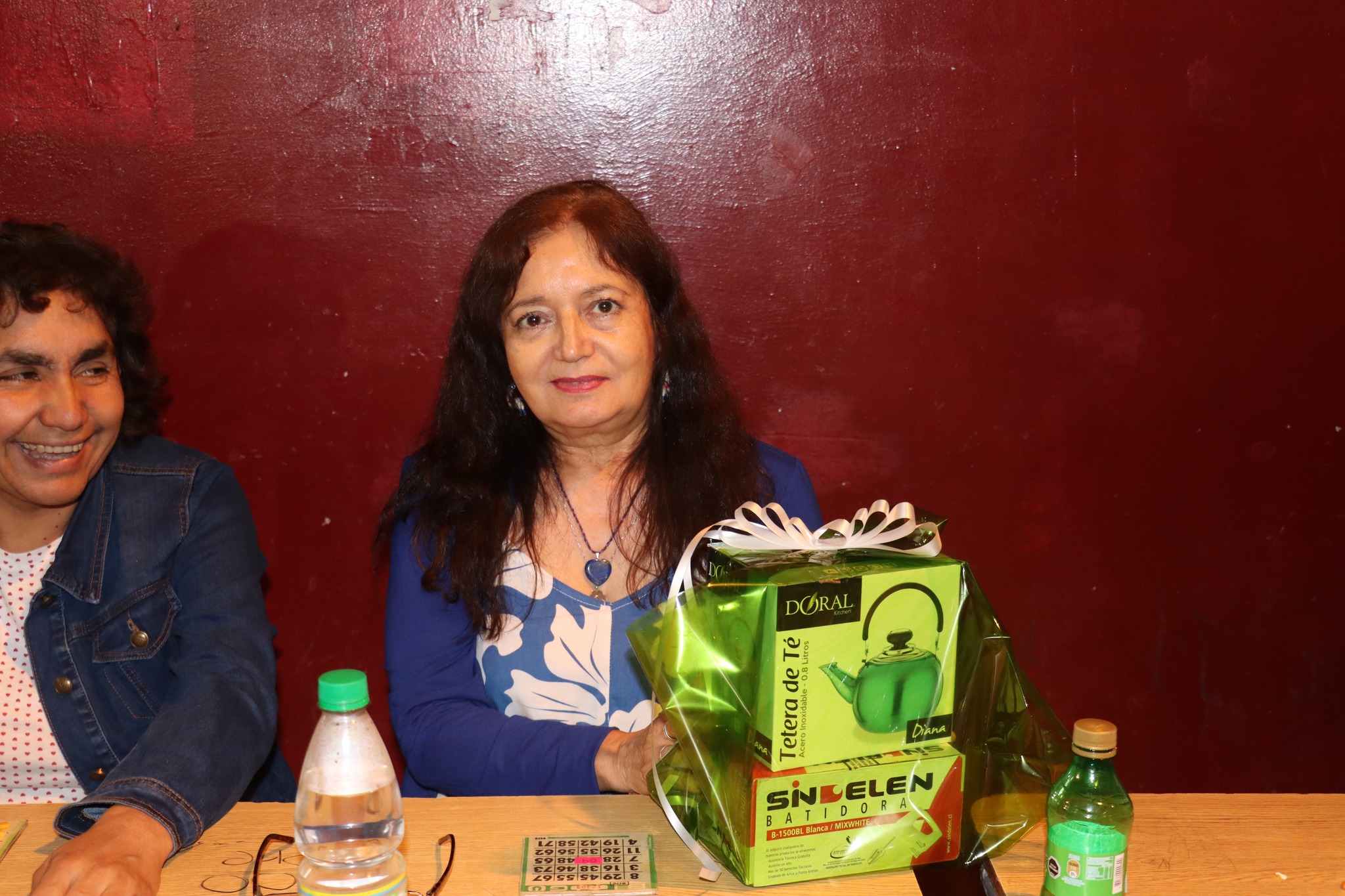 Ganadora posa con un set de tetera y productos como premio del Gran Bingo Veraniego en Plaza Prat, Taltal.