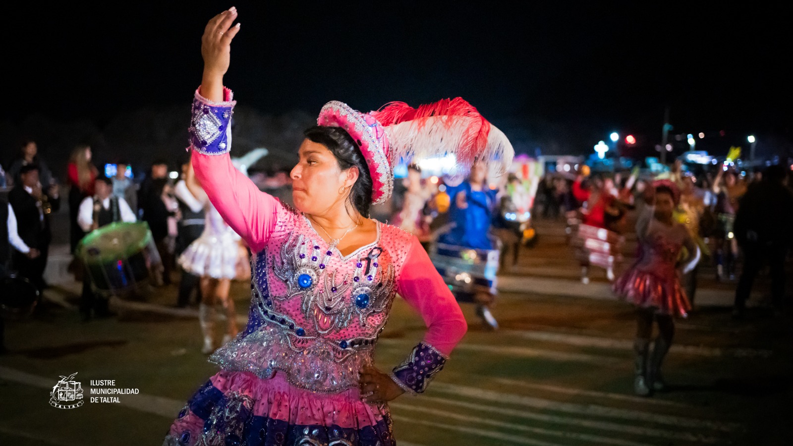 Bailarina en traje rosa y sombrero emplumado alzando el brazo en procesión nocturna Virgen de Lourdes La Puntilla Taltal febrero 2026