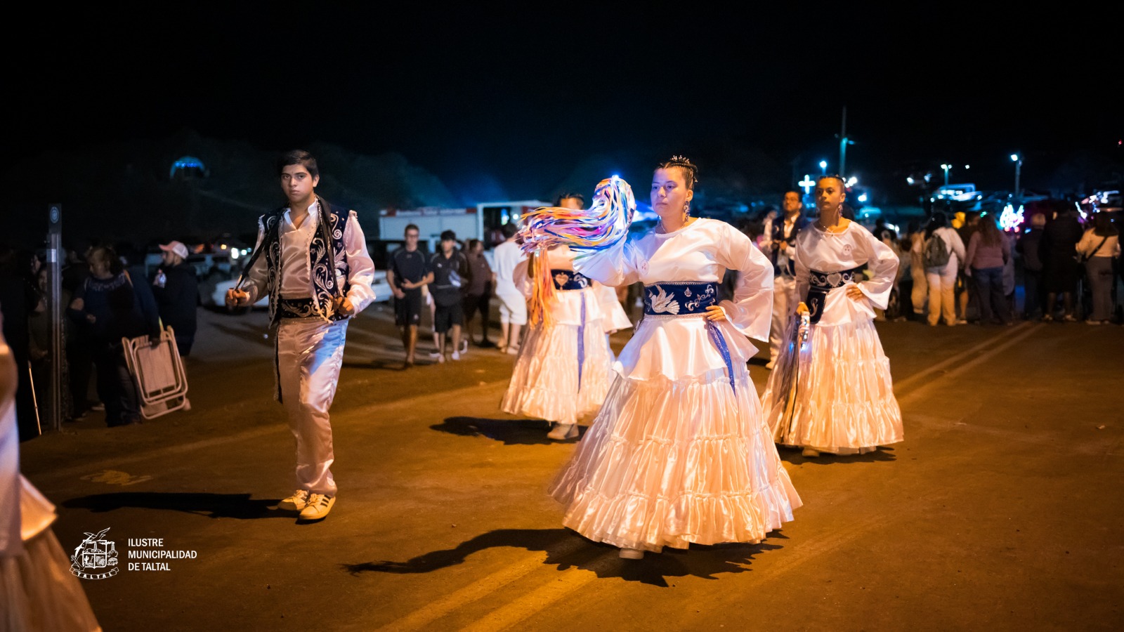 Bailarinas religiosas con trajes blancos y flecos coloridos en procesión nocturna Fiesta Virgen de Lourdes La Puntilla Taltal 2026