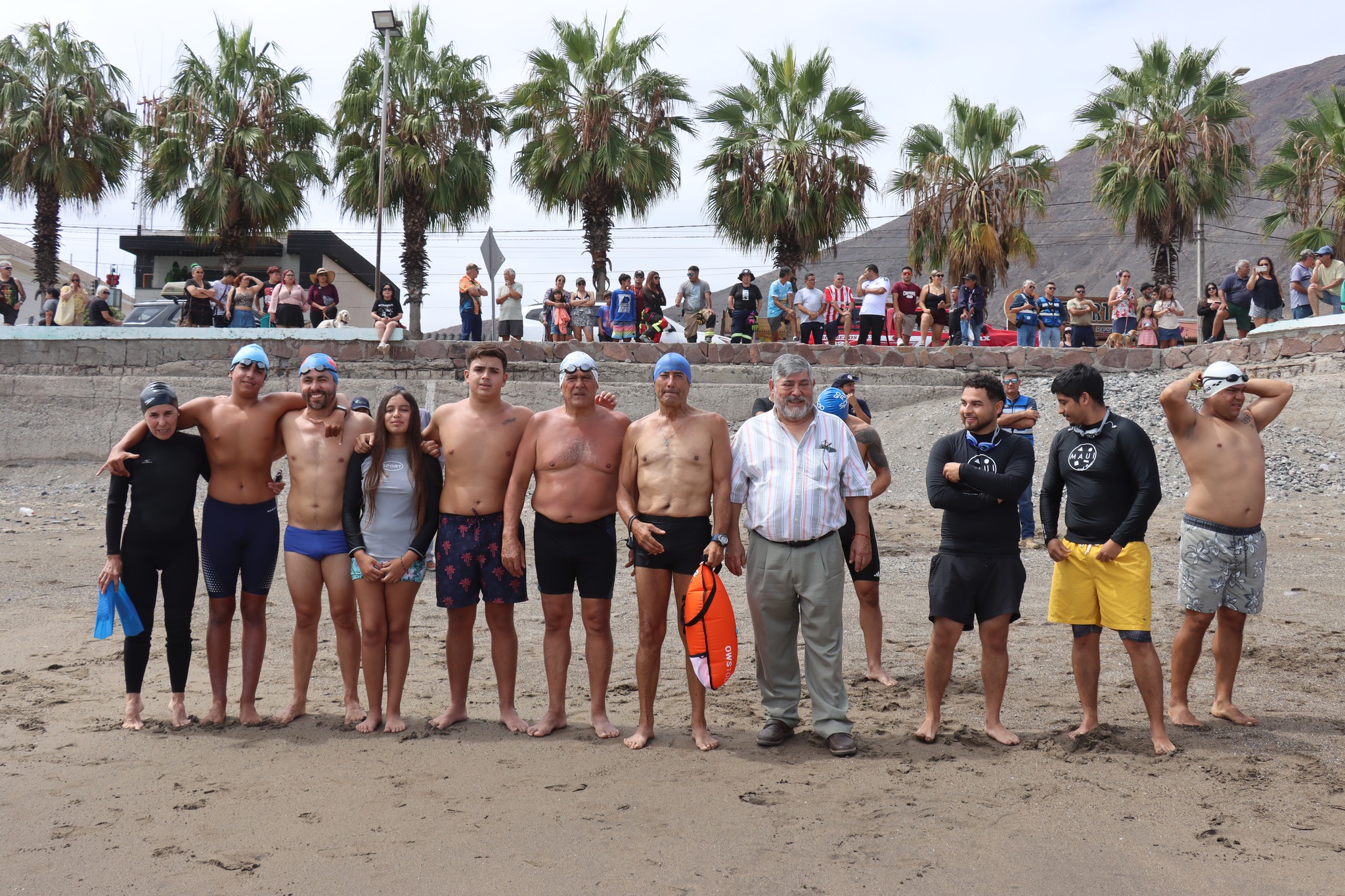 Formación de nadadores con Tarzán Álvarez en centro antes de travesía honor Virgen de Lourdes La Puntilla Taltal 2026.