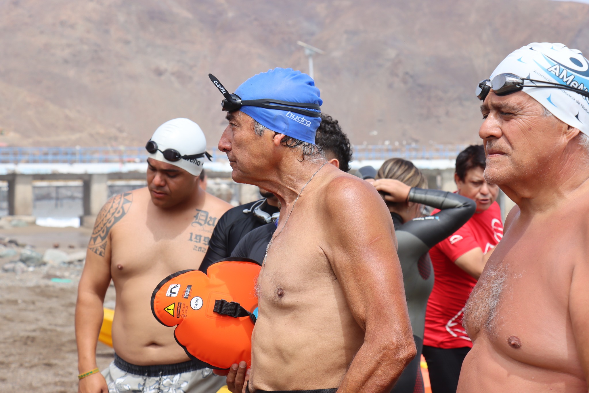 Tarzán Álvarez junto a grupo de nadadores durante preparación o salida en travesía honor Virgen de Lourdes sector La Puntilla Taltal 2026.