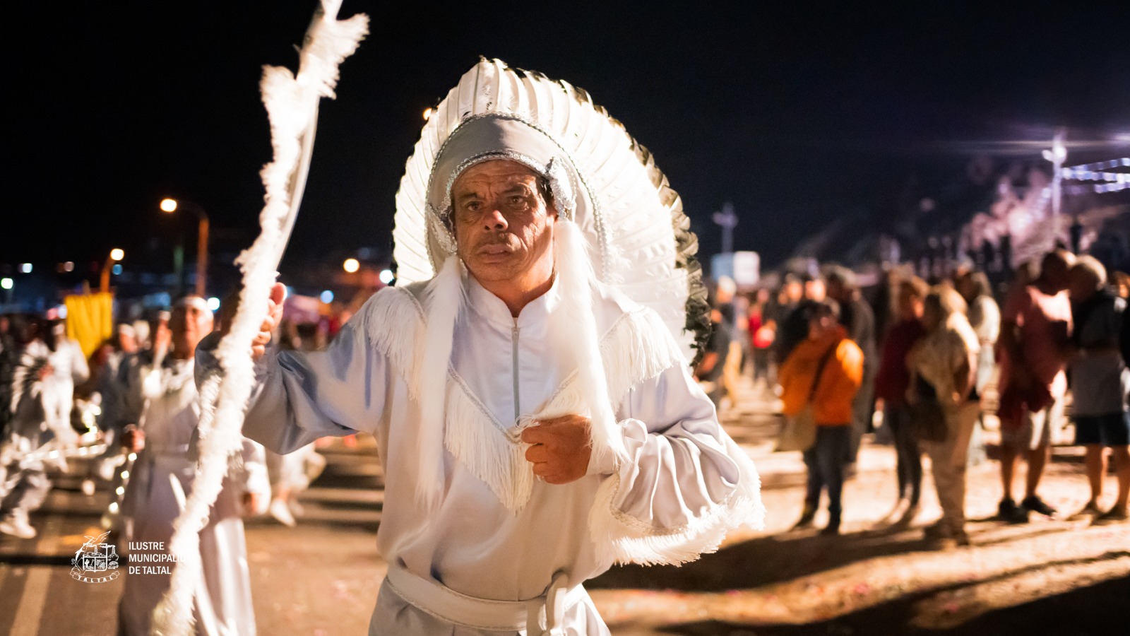 Bailarín en traje blanco con plumas largas participando en procesión nocturna Virgen de Lourdes La Puntilla Taltal febrero 2026