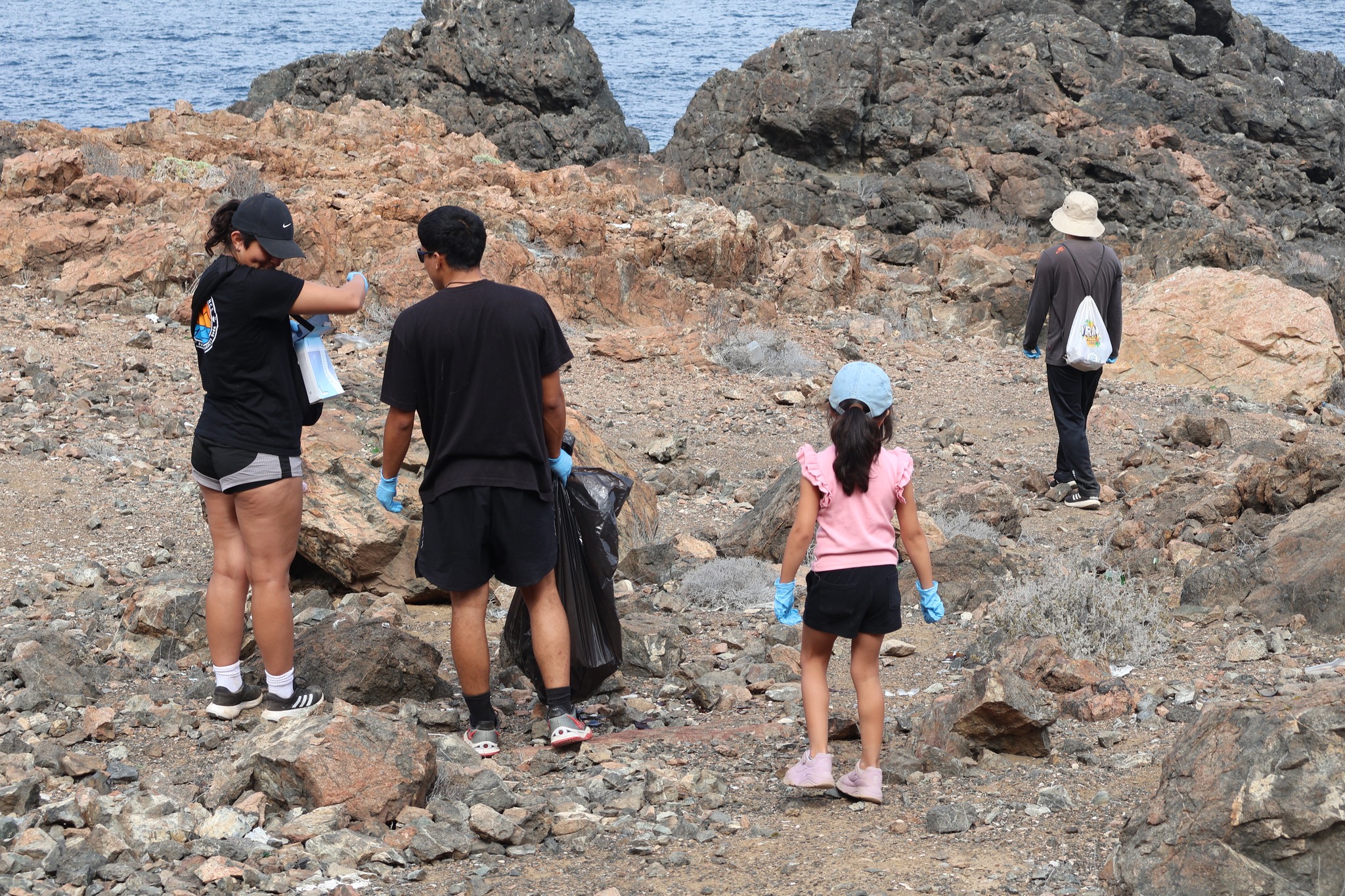 Familias y niños participan con guantes en jornada de limpieza del Sitio Arqueológico Los Vientos, Taltal, promoviendo conciencia y respeto por el patrimonio Chango (febrero 2026).