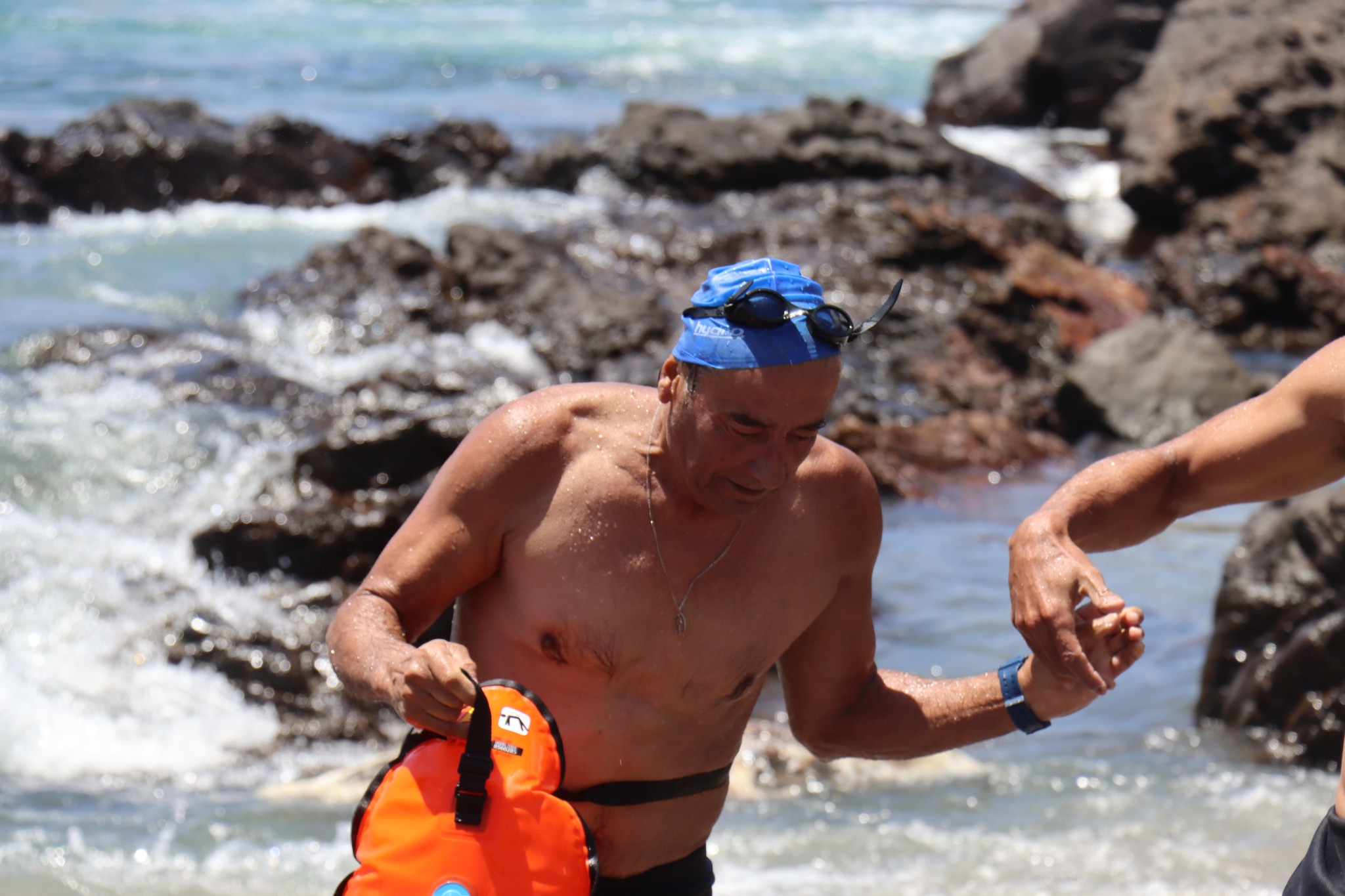 Tarzán Álvarez emerge del mar con chaleco salvavidas tras 26° travesía a nado honor Virgen de Lourdes La Puntilla Taltal febrero 2026.