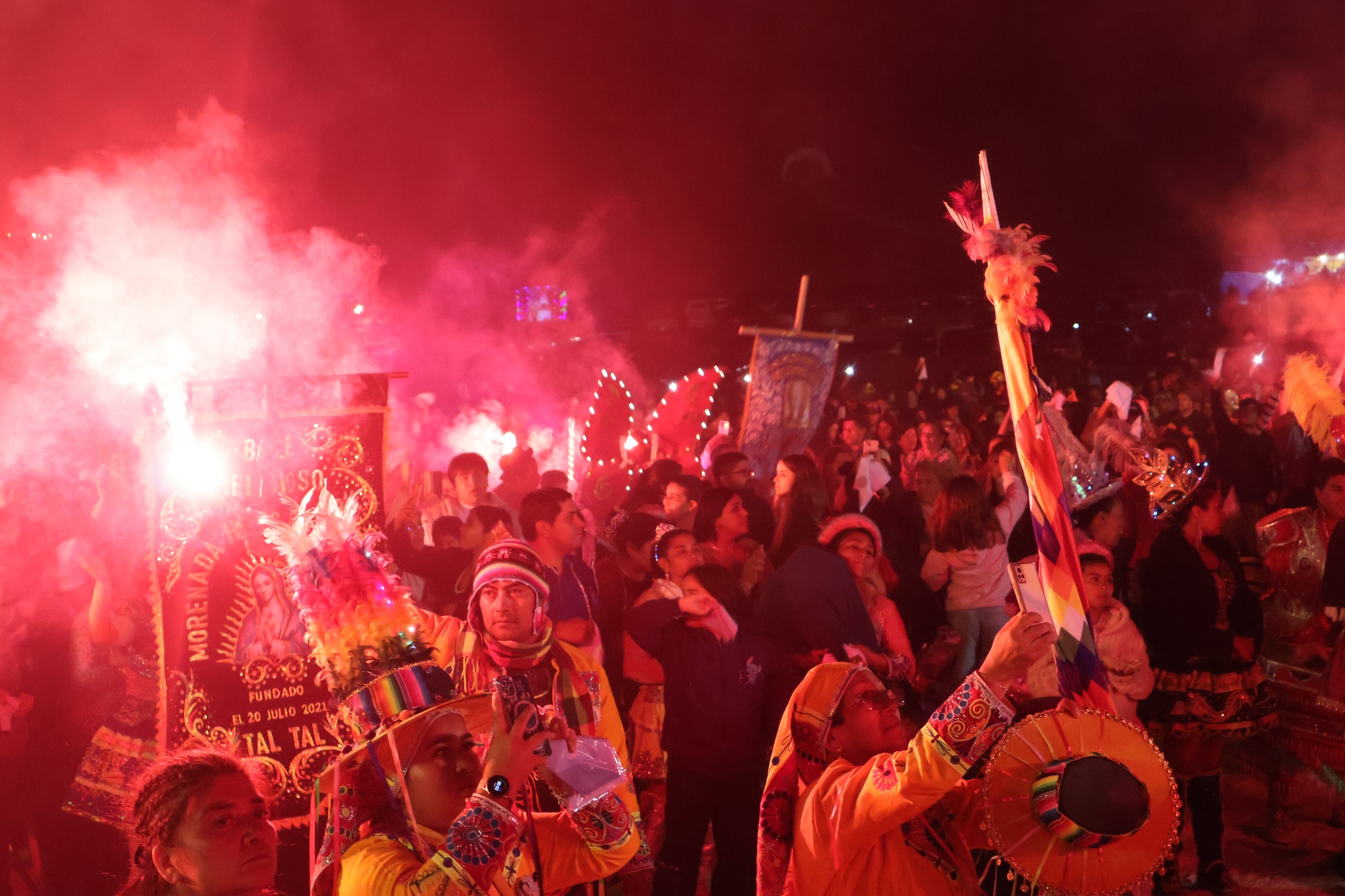 Multitud con banderas y estandartes rodeando la imagen de Virgen de Lourdes en procesión nocturna La Puntilla Taltal 2026