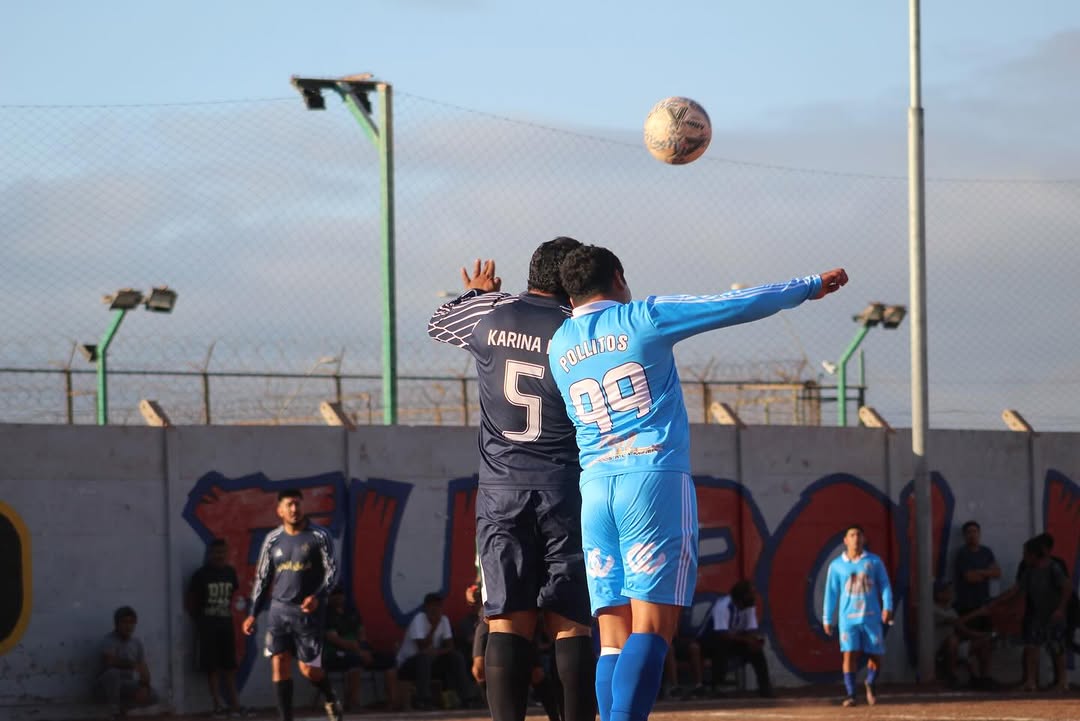Jugadores de Karina FC y Pollitos x Siempre disputan un balón aéreo en la cancha Thompson con Ramírez, semifinal Futbolito Taltal 2026.