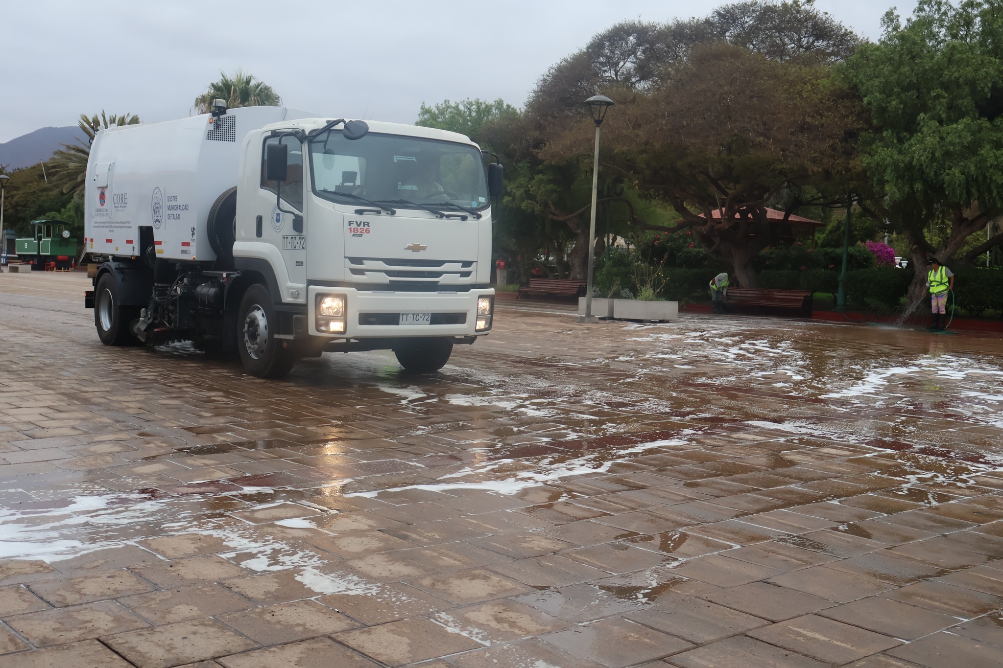 Camión barredor municipal de la Ilustre Municipalidad de Taltal en operativo de limpieza profunda en Plaza Prat, con espuma sobre el pavimento.<br />
