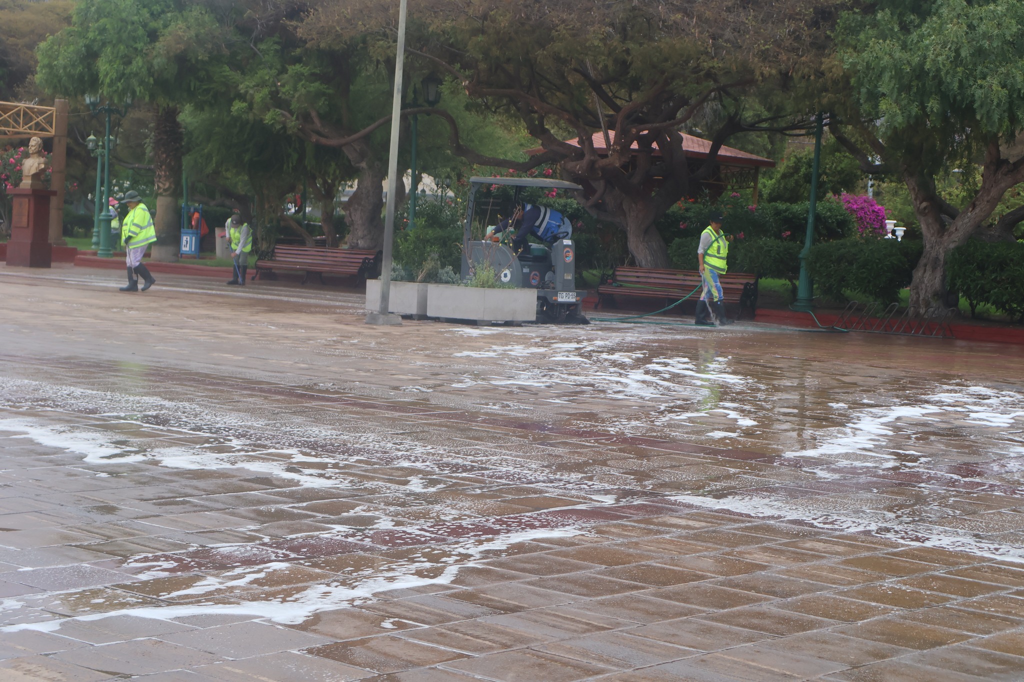 Equipo de funcionarios municipales de Taltal en operativo de limpieza profunda en Plaza Prat con barredora y mangueras.