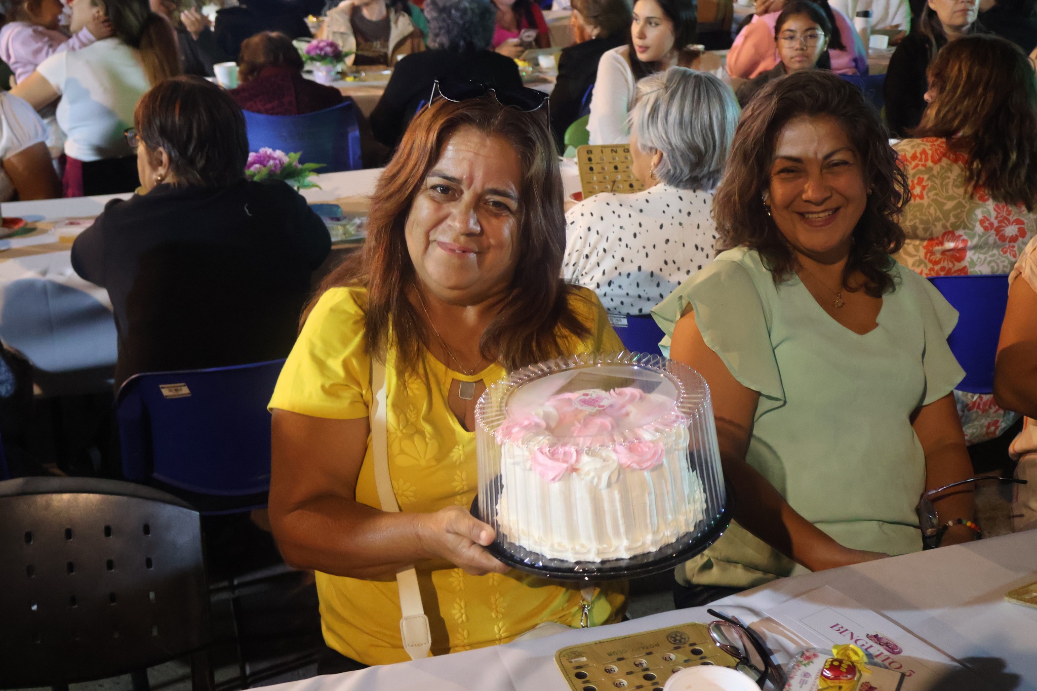 Mujer ganadora muestra torta premio bingo Día Mujer Taltal