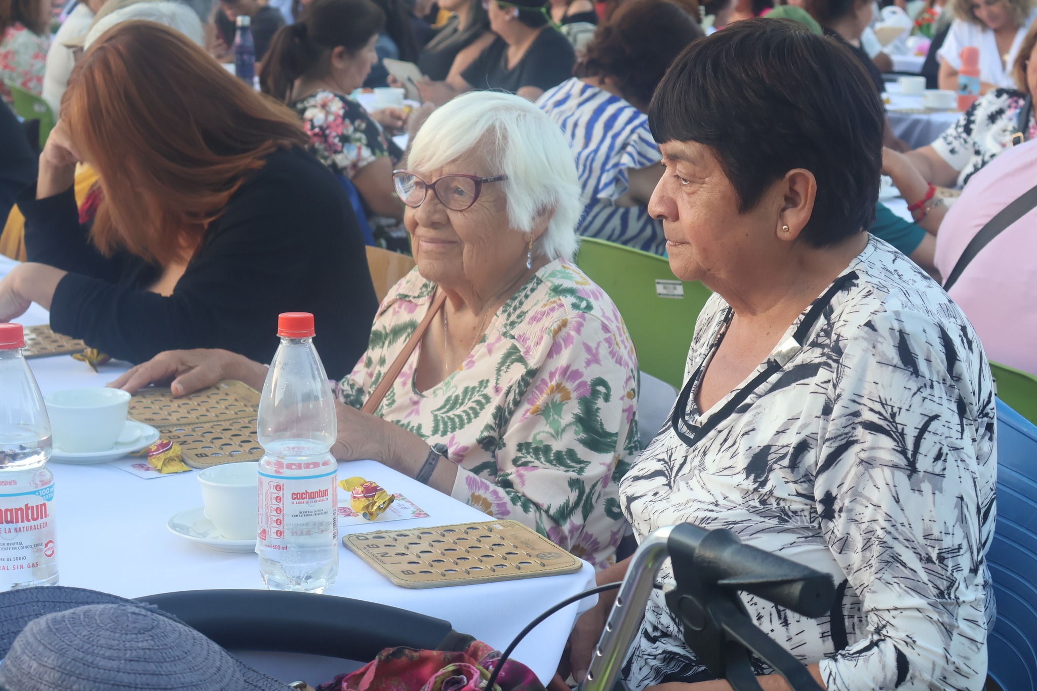 Adultas mayores participan con cartones de bingo en actividad del Día Internacional de la Mujer en Taltal.