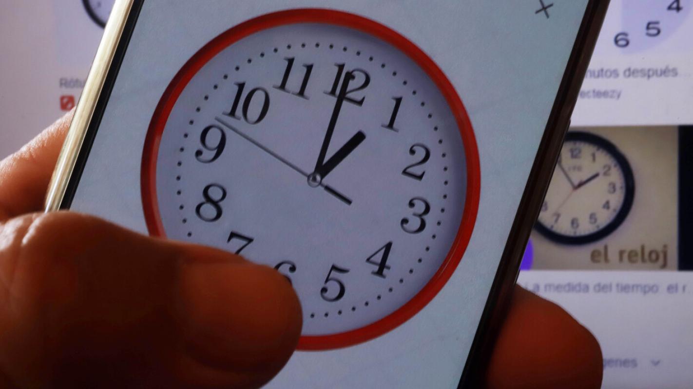 Celular con reloj análogo en pantalla durante el cambio de hora en Chile